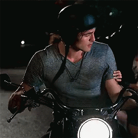 A Man Wearing A Helmet Is Riding A Motorcycle With A Woman Hugging Him . GIF