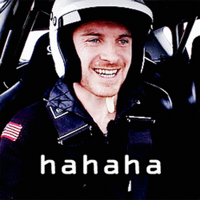A Man Wearing A Helmet Is Smiling In A Car With The Word Hahaha Written Below Him GIF