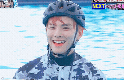A Man Wearing A Helmet Is Smiling In Front Of A Sign That Says Next . GIF