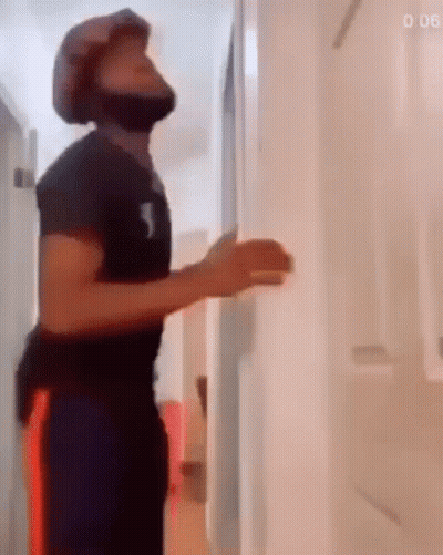 A Man Wearing A Helmet Is Standing In A Hallway . GIF