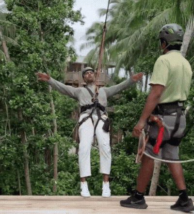A Man Wearing A Helmet Is Standing Next To A Woman Wearing A Helmet On A Zip Line GIF
