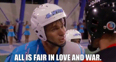 A Man Wearing A Helmet Is Talking To Another Man While A Cheerleader Stands In The Background . GIF