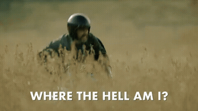 A Man Wearing A Helmet Is Walking Through A Field And Asking Where The Hell Am I . GIF