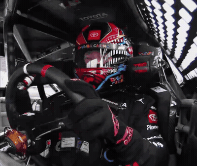 A Man Wearing A Helmet That Says Toyota Is Driving A Car GIF