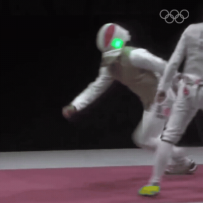 A Man Wearing A Helmet With A Green Light On It Is Playing Fencing Against Another Man . GIF