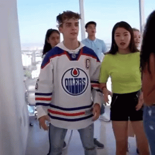 A Man Wearing A Hockey Jersey Is Standing Next To A Woman In A Neon Green Shirt . GIF