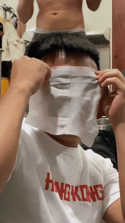 A Man Wearing A Hong Kong T-Shirt Covers His Face With A Piece Of Paper GIF