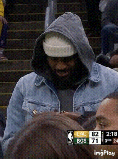 A Man Wearing A Hooded Jacket And A Beanie Stands In Front Of A Scoreboard That Says Lal Bos 71 GIF