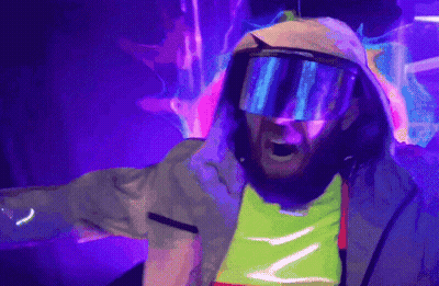 A Man Wearing A Hooded Jacket And Goggles Is Standing In Front Of A Purple Background GIF