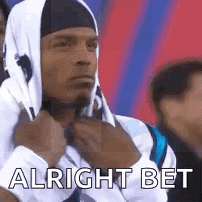 A Man Wearing A Hooded Sweatshirt And A Headband Is Sitting In A Crowd Of People . GIF