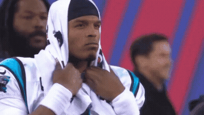 A Man Wearing A Hooded Sweatshirt And A Headband Is Standing In A Stadium . GIF