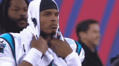 A Man Wearing A Hooded Sweatshirt And A Headband Is Standing In Front Of A Crowd . GIF
