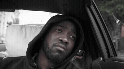 A Man Wearing A Hooded Sweatshirt Is Sitting In A Car GIF