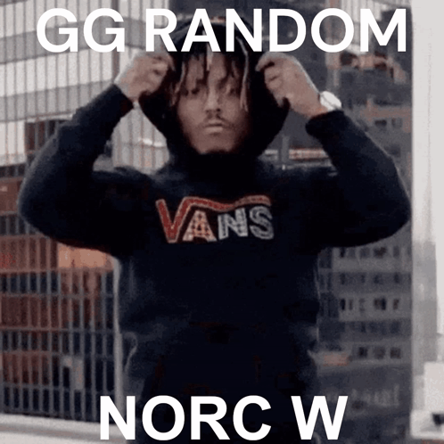 A Man Wearing A Hoodie And A Vans Shirt Is Standing On A Balcony . GIF