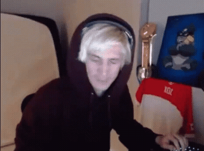 A Man Wearing A Hoodie And Headphones Is Sitting In Front Of A Computer . GIF
