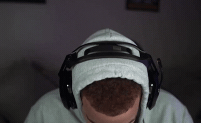 A Man Wearing A Hoodie And Headphones Is Sitting In Front Of A Computer . GIF