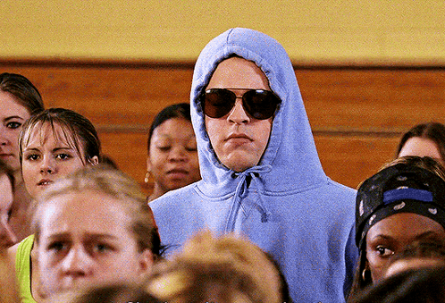 A Man Wearing A Hoodie And Sunglasses Is Surrounded By A Crowd Of People GIF