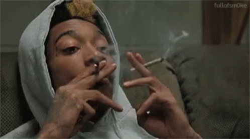 A Man Wearing A Hoodie Is Smoking A Cigarette . GIF