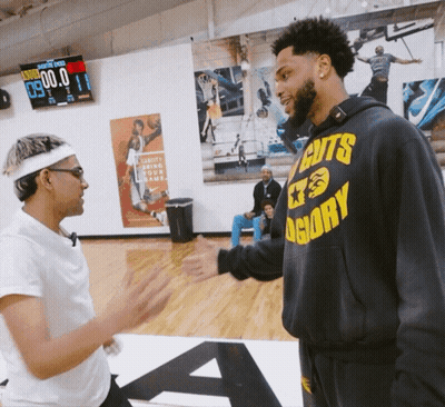 A Man Wearing A Hoodie That Says Cuts Glory Shakes Hands With Another Man GIF