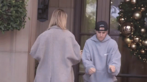 A Man Wearing A Hoodie That Says ' Justin Bieber ' On It Is Standing Next To A Woman GIF