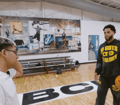 A Man Wearing A Hoodie That Says No Guts Glory Talks To Another Man GIF