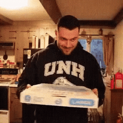 A Man Wearing A Hoodie That Says Unh Is Holding A Box GIF