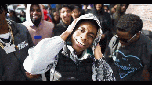 A Man Wearing A Hoodie With The Word Conquer On It Stands In A Crowd GIF