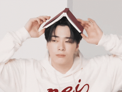 A Man Wearing A Hoodie With The Word Mais On It Holds A Book On His Head GIF