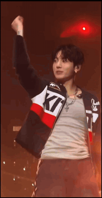 A Man Wearing A Jacket That Says Kt Is Raising His Fist In The Air GIF