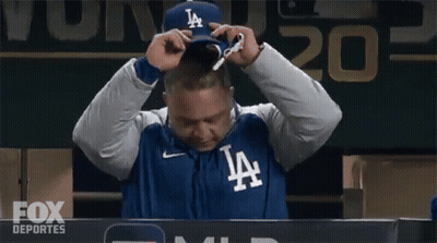 A Man Wearing A Jacket That Says La Is Sitting In Front Of A Scoreboard GIF