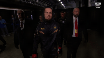 A Man Wearing A Jacket That Says Ufc Is Walking In A Dark Room GIF