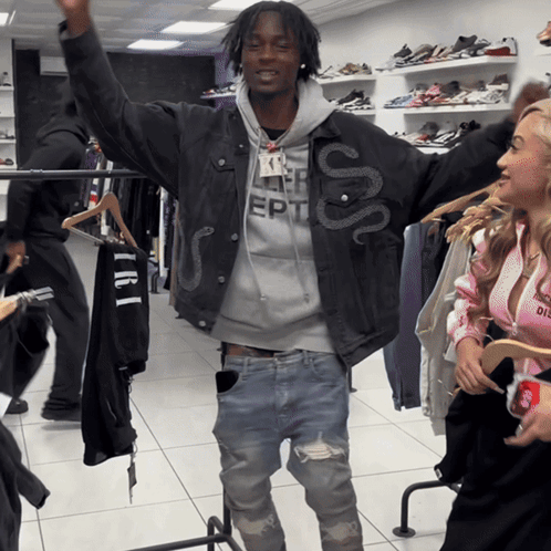 A Man Wearing A Jacket With A Snake On It Stands In A Store GIF
