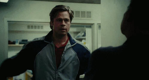 A Man Wearing A Jacket With The Word Nike On It Stands In Front Of A Refrigerator GIF