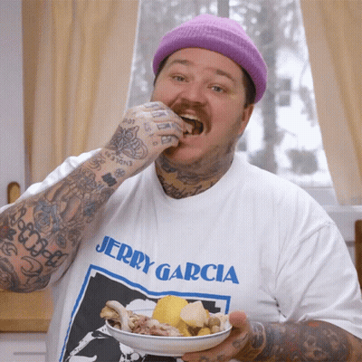 A Man Wearing A Jerry Garcia T-Shirt Is Eating Food From A Plate GIF
