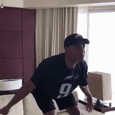 A Man Wearing A Jersey With The Number 9 On It Is Jumping On A Couch GIF