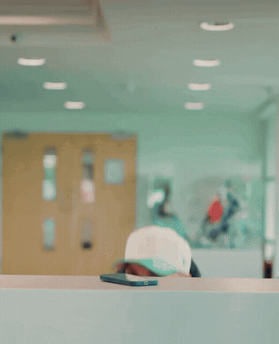A Man Wearing A Kappa Jacket Is Smiling While Sitting At A Counter GIF