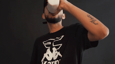 A Man Wearing A Kappa T-Shirt Is Drinking From A Cup GIF