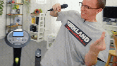 A Man Wearing A Kirkland T-Shirt Sings Into A Microphone GIF