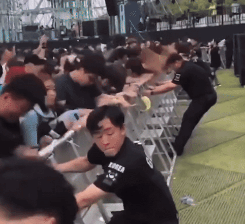 A Man Wearing A Korea Shirt Is Standing In Front Of A Crowd Of People GIF