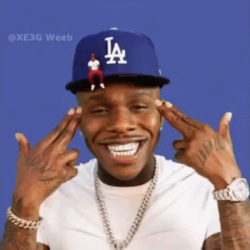 A Man Wearing A La Hat And A White Shirt Is Making A Peace Sign . GIF