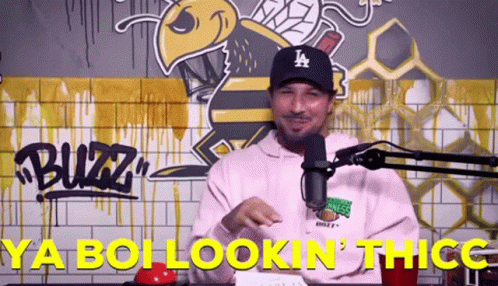 A Man Wearing A La Hat Is Standing In Front Of A Microphone And Says Ya Boi Lookin ' Thicc GIF