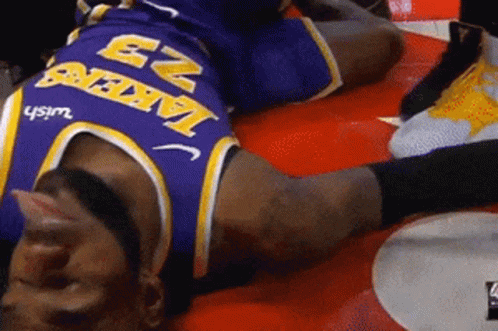 A Man Wearing A Lakers Jersey Is Laying On The Ground GIF