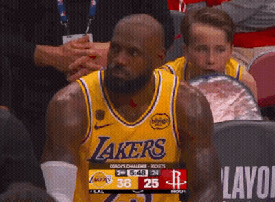 A Man Wearing A Lakers Jersey Sits In The Stands Watching A Game GIF