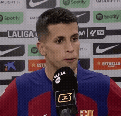 A Man Wearing A Laliga Jersey Is Talking Into A Microphone . GIF