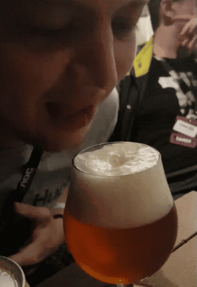 A Man Wearing A Lanyard That Says ' Ncs ' On It Looks At A Glass Of Beer GIF