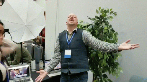 A Man Wearing A Lanyard With A Name Tag That Says ' Chris ' On It Stands With His Arms Outstretched GIF