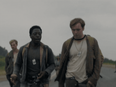 A Man Wearing A Lanyard With The Number 49 On It Walks Down A Road GIF