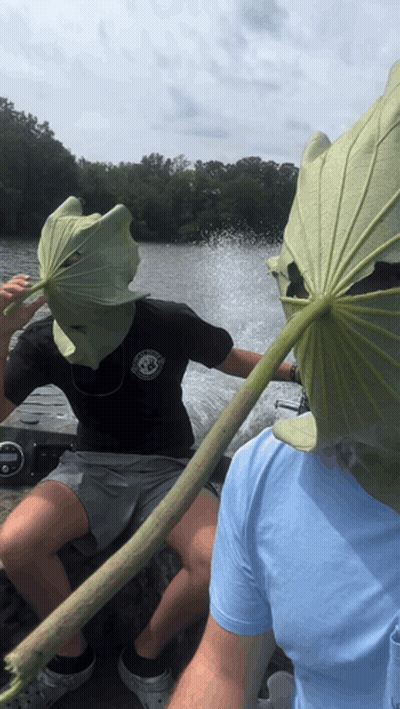 A Man Wearing A Leaf Mask Is Sitting On A Boat Next To Another Man GIF