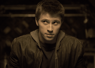 A Man Wearing A Leather Jacket And A Hoodie Looks To His Left GIF