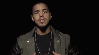 A Man Wearing A Leather Jacket And A Necklace Is Making A Funny Face With His Hands In The Air . GIF